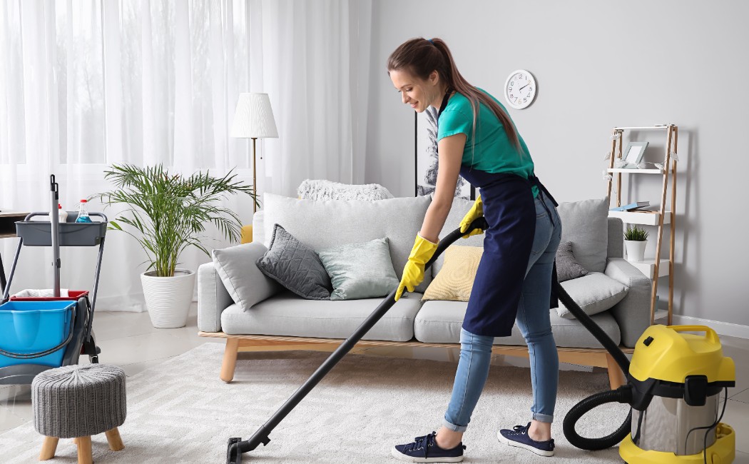 Residential Cleaning Services professional vacuuming a living room carpet in a bright, modern home.