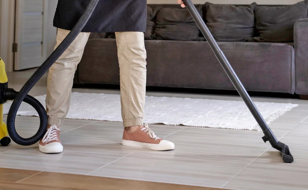 Cleaner vacuuming the floor in a modern living room as part of professional Airbnb Cleaning Services.