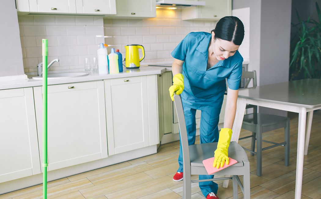 Professional cleaner disinfecting kitchen chairs in a modern rental apartment for Airbnb Cleaning Services.