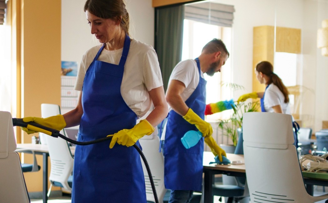Cleaning team sanitizing office furniture and workspaces while performing professional commercial cleaning services in a modern office environment.
