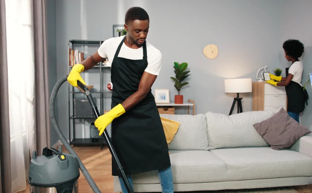 Cleaning experts vacuuming and dusting a living room to maintain a spotless and hygienic home environment.