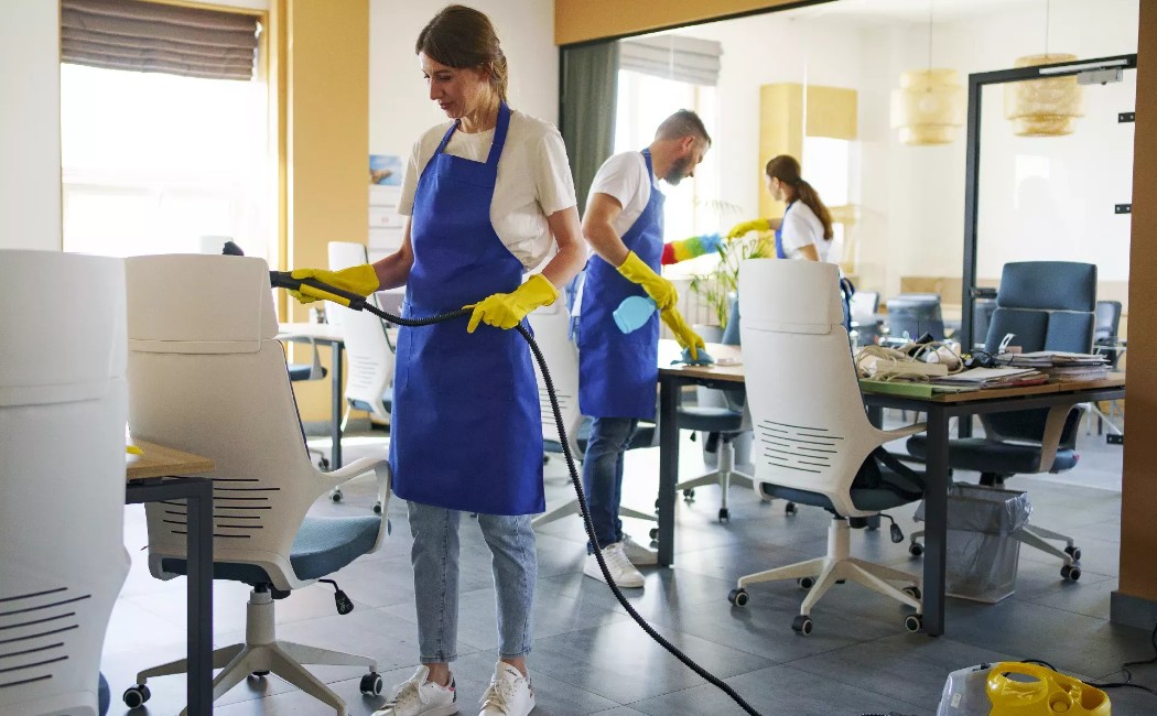 Office Cleaning professionals sanitizing desks, chairs, and workspaces in a modern office environment.