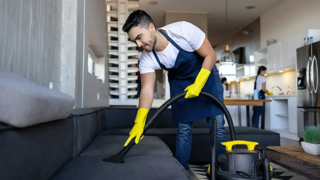 Airbnb Cleaning Experts deep-cleaning a sofa with professional vacuum equipment.