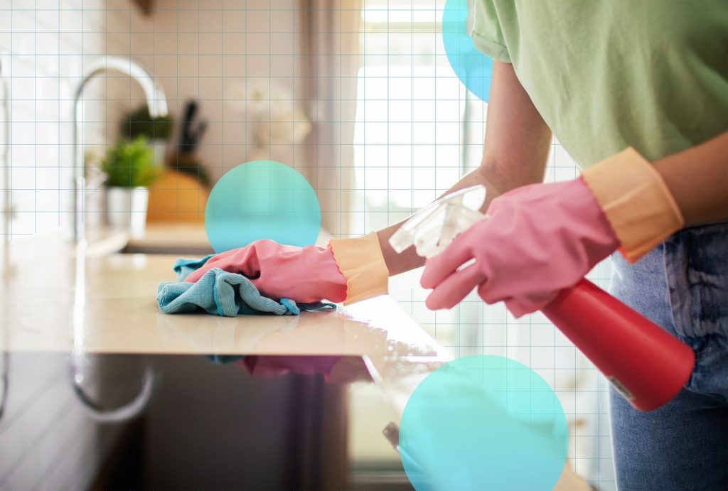 A professional cleaner wipes a kitchen countertop with a cloth and spray bottle during thorough Kitchen Cleaning for a fresh, spotless space.
