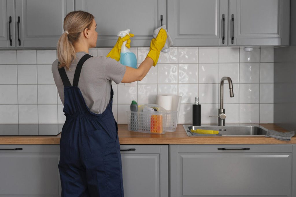 Kitchen Cleaning Service professional cleaning a modern kitchen, wiping cabinets and surfaces with cleaning supplies for a spotless, fresh home