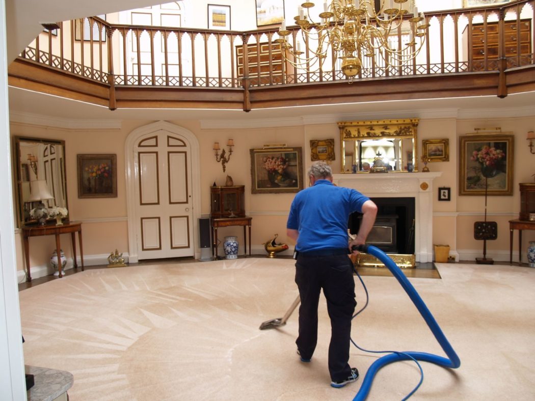 A residential cleaning professional deep-cleans a luxurious home’s carpet, restoring freshness and a spotless, inviting living space.