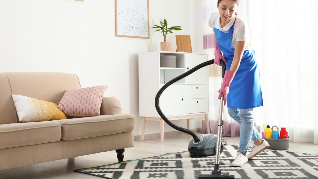 Patterned Rug Cleaning in Living Room A residential cleaning specialist is vacuuming a patterned rug in a bright living room for a fresh, spotless, and welcoming home.